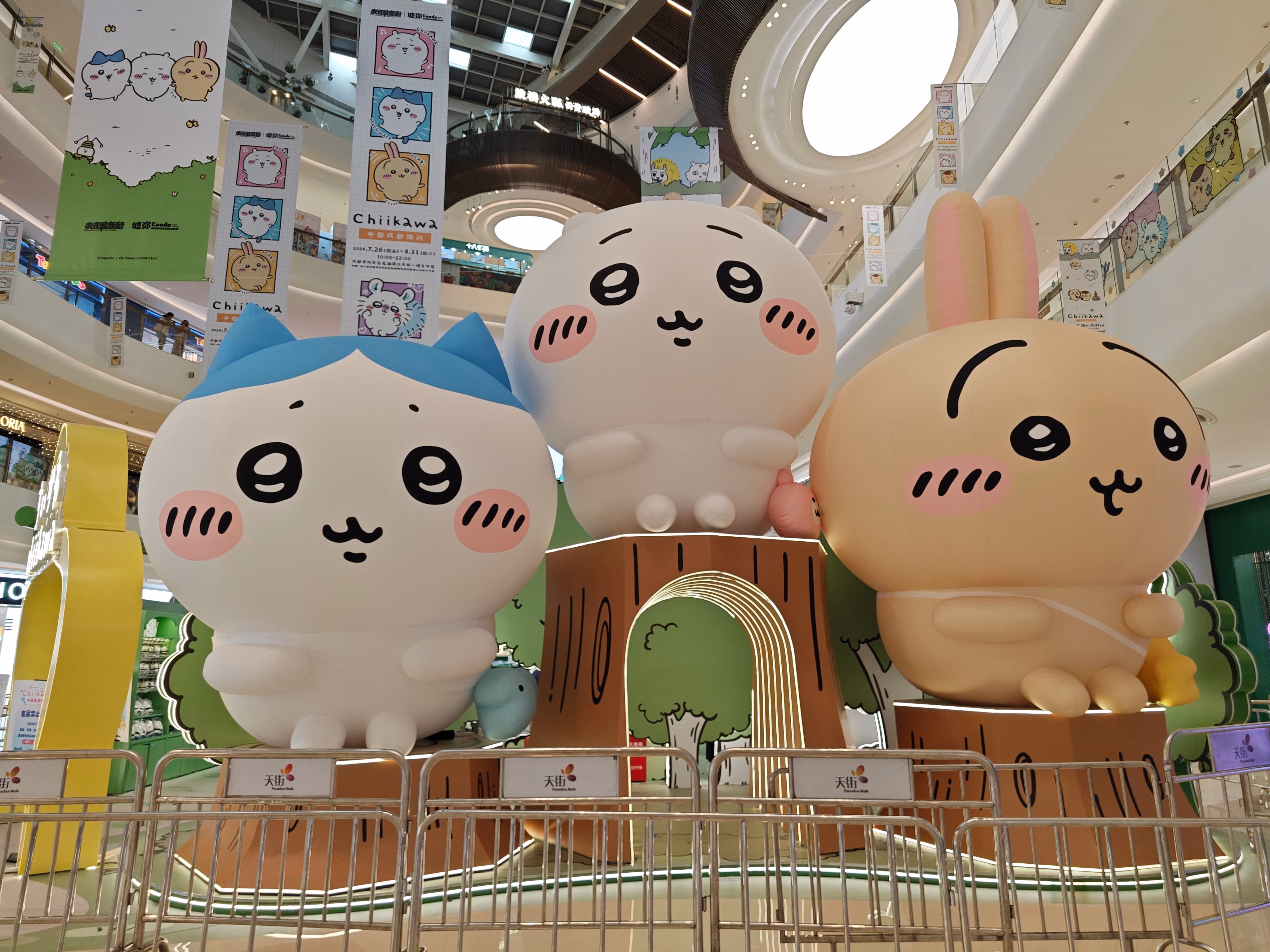 The image shows three large cartoon animal statues, resembling raccoons or bunnies, displayed on a platform in a shopping mall. (由 AI 生成标题)