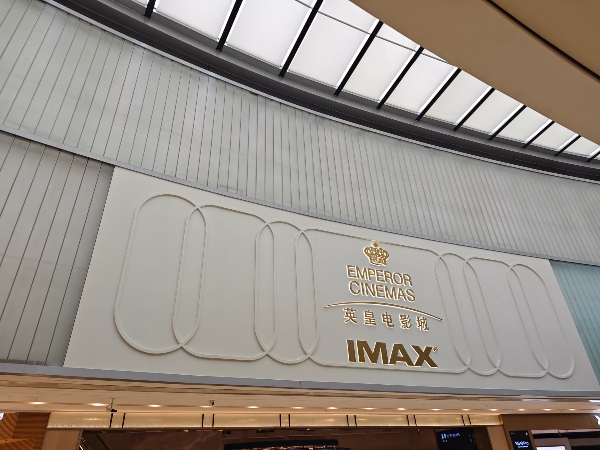 The image shows a sign for Emperor Cinemas, featuring the words "Emperor Cinemas" in gold lettering, accompanied by Chinese characters and the IMAX logo. (由 AI 生成标题)
